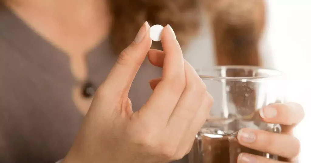 Woman's hand holding white pill