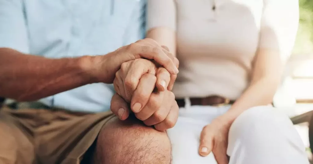 middle age couple holding hands supportively