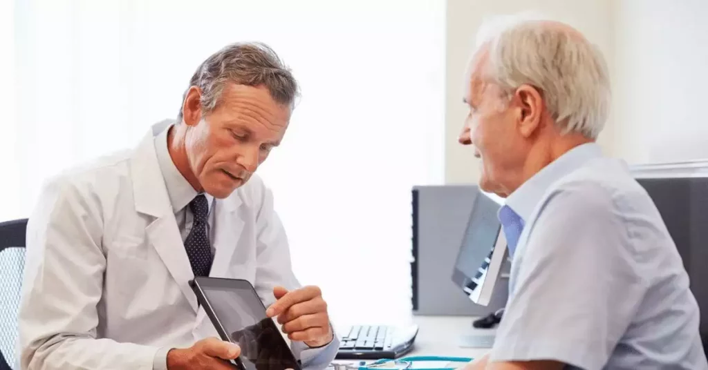 Male doctor and elderly patient with x-ray tablet discussing migraine vertigo