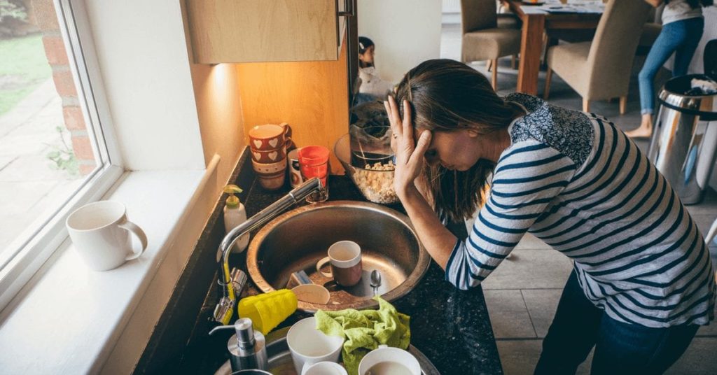 a woman rubbing her temples in her kitchen