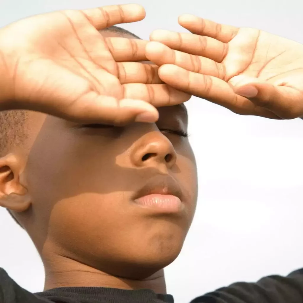 Boy blocking the sun with his hands