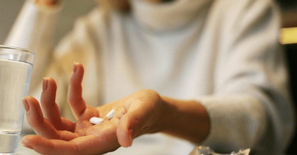 Patient holding pills - medication overuse headache header