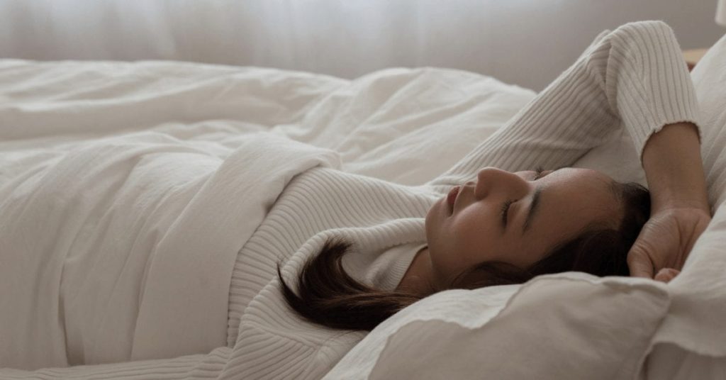 Woman with headache lying in bed