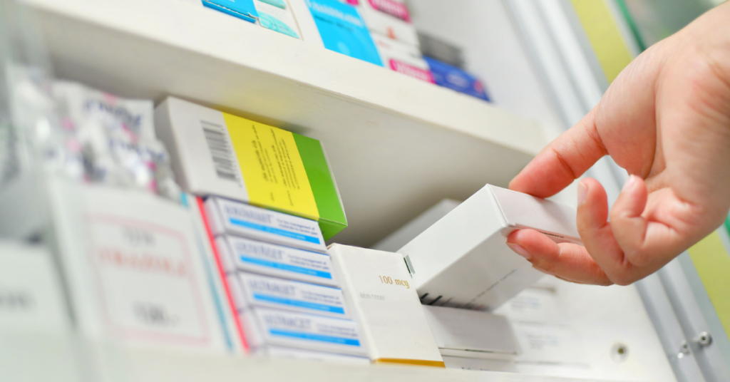 pharmacist pulling medication box from shelf