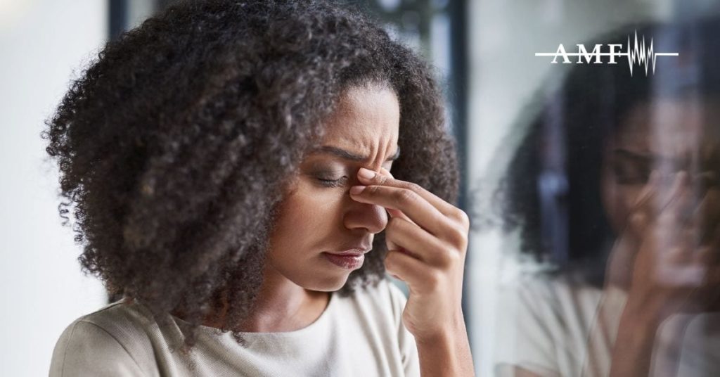 woman with headache pinching bridge of nose